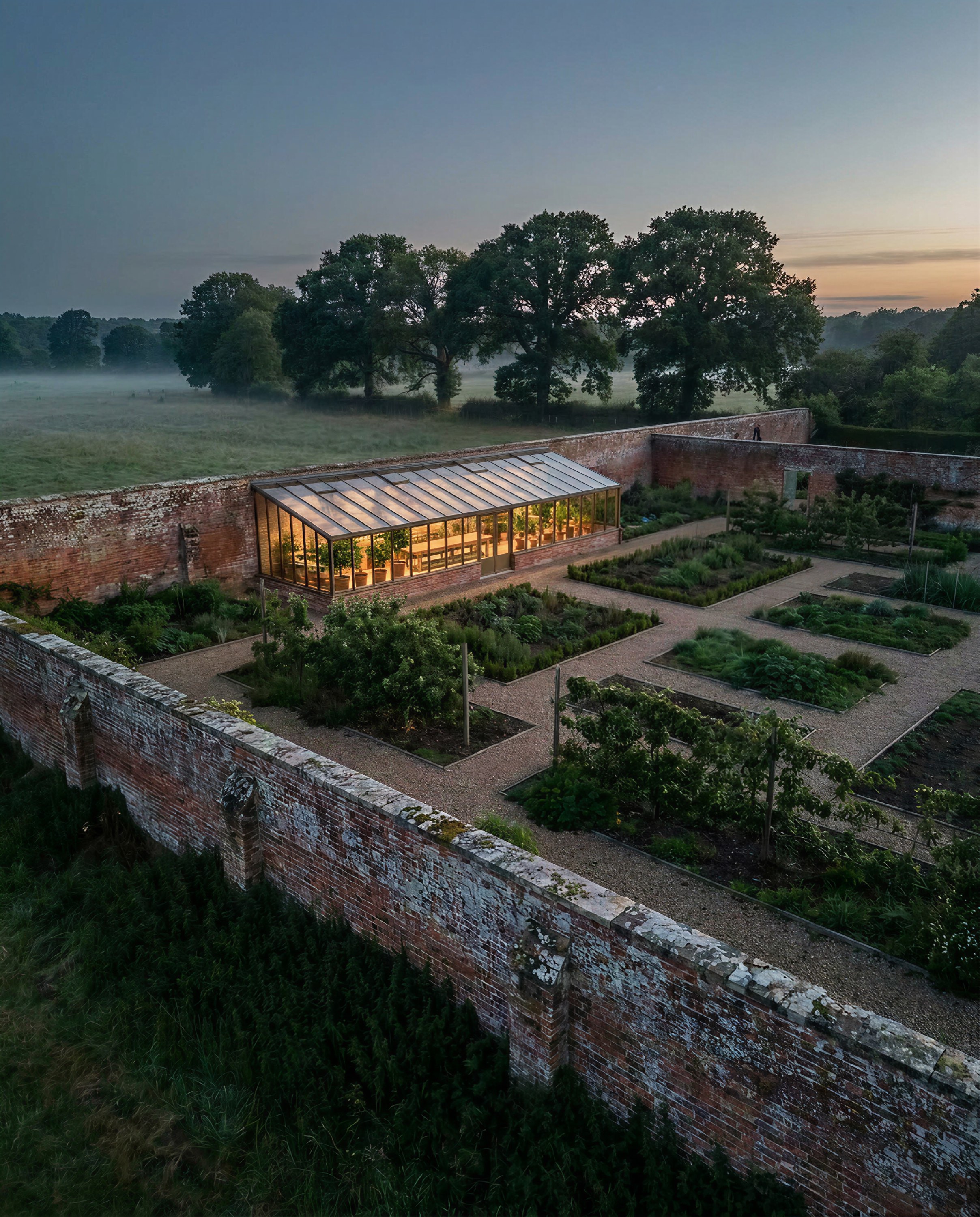 Victorian greenhouse glowing in a walled kitchen garden at dawn