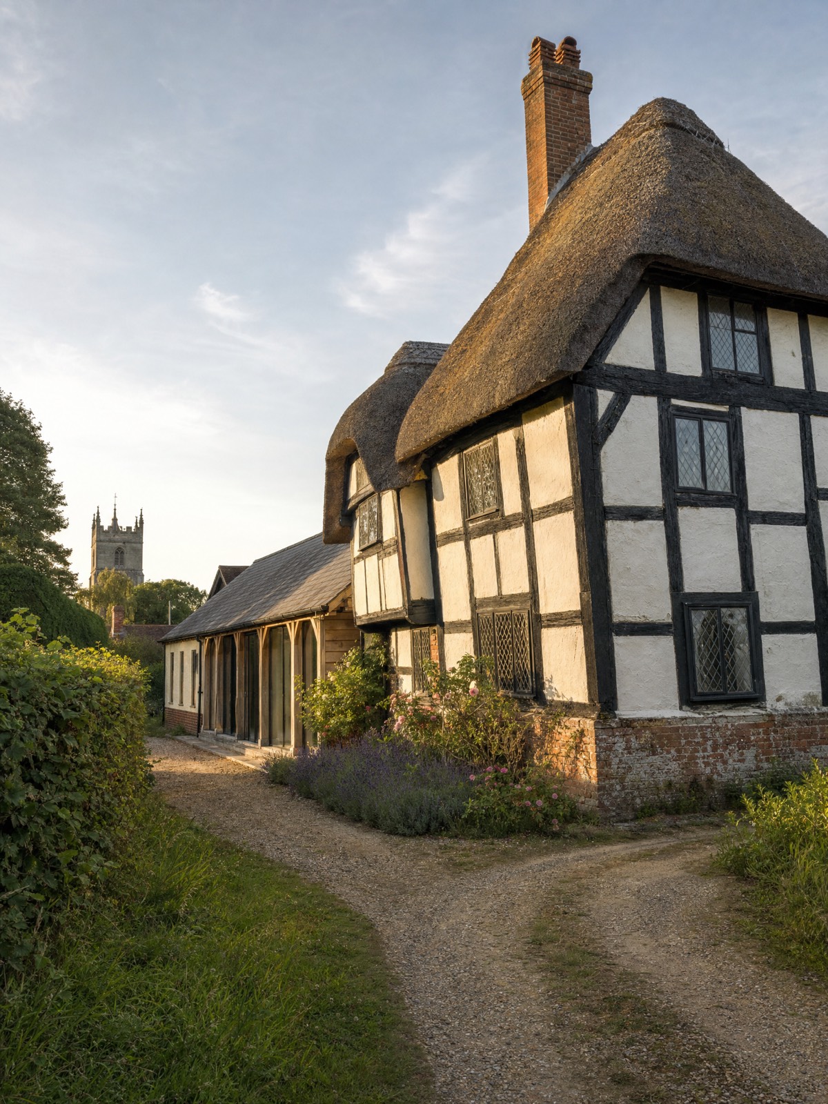 Thatched timber-framed cottage on a village lane at golden hour